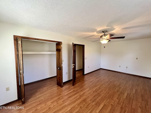 unfurnished bedroom featuring baseboards, wood finished floors, and a textured ceiling