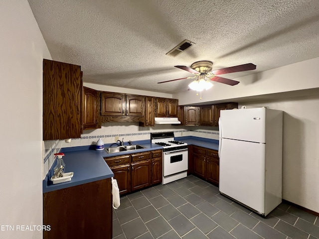 kitchen with dark tile patterned floors, a sink, white appliances, and visible vents