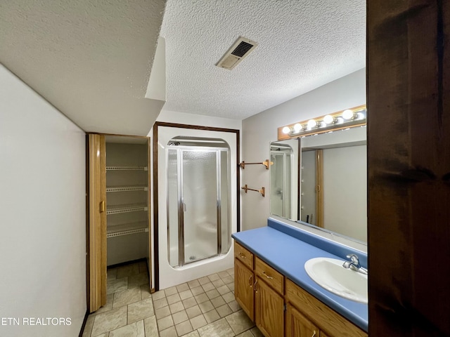 bathroom with vanity, a stall shower, tile patterned flooring, a textured ceiling, and visible vents