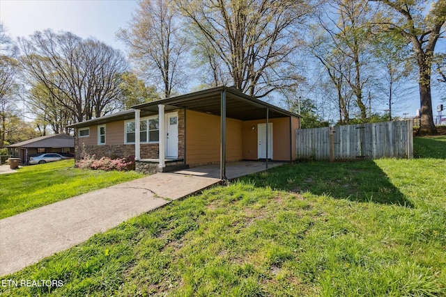 mid-century home with concrete driveway, a carport, stone siding, a front lawn, and fence