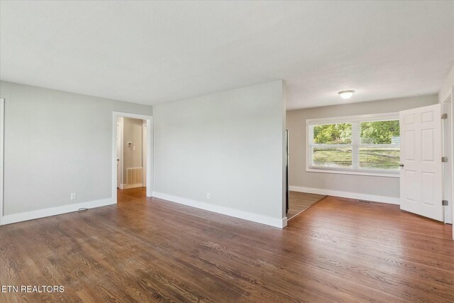 unfurnished room with wood finished floors, baseboards, and visible vents