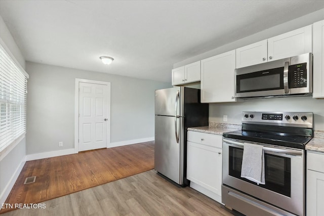 kitchen featuring baseboards, white cabinetry, visible vents, appliances with stainless steel finishes, and light wood finished floors