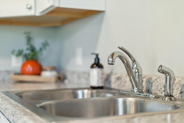 details with a sink and white cabinetry