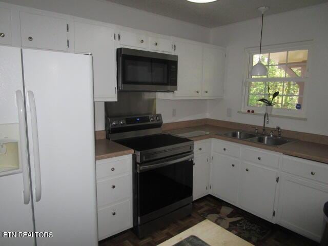 kitchen with pendant lighting, white cabinetry, a sink, and appliances with stainless steel finishes