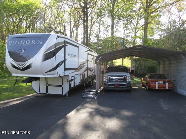 view of car parking with driveway and a detached carport