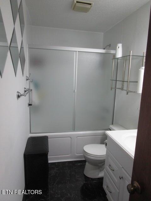 bathroom featuring toilet, vanity, visible vents, and bath / shower combo with glass door