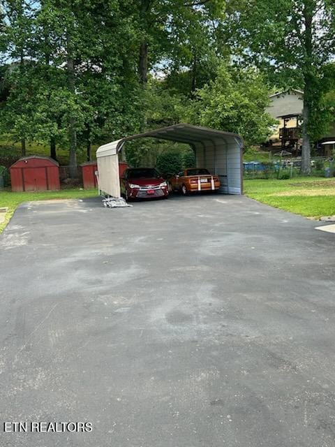 6408 NW Ellesmere Dr, Knoxville, TN 37921 - view of parking / parking lot featuring driveway, a storage shed, a carport, and view of scattered trees