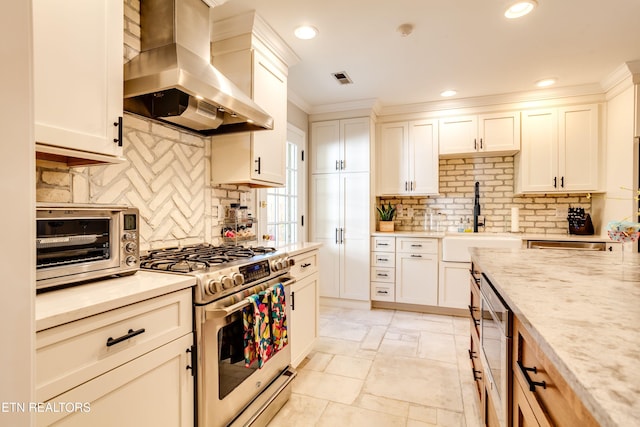 3835 SW Keowee Ave, Knoxville, TN 37919 - kitchen featuring stainless steel gas range oven, stone tile flooring, wall chimney exhaust hood, decorative backsplash, and a sink