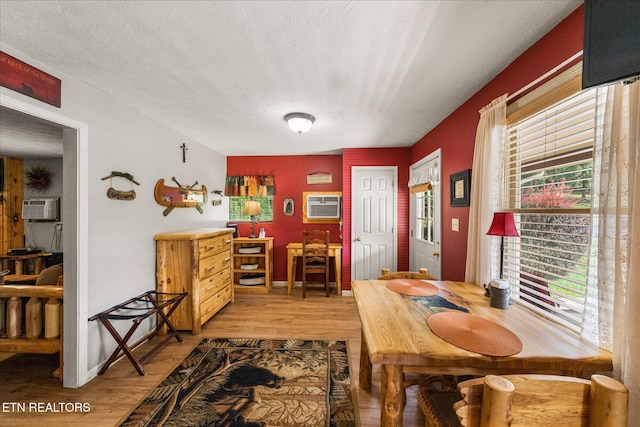 dining space featuring light wood-style flooring, an AC wall unit, and baseboards