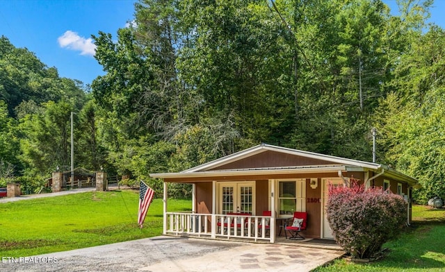 exterior space with a porch, french doors, a wooded view, and a lawn