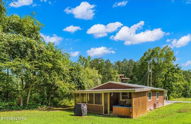 exterior space with a wooded view, a sunroom, and a lawn