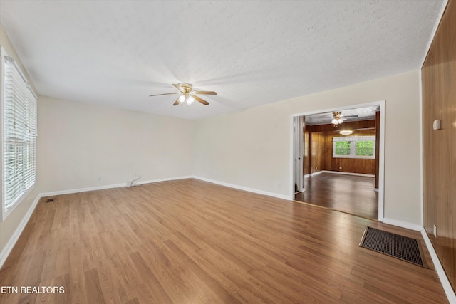 spare room featuring visible vents, ceiling fan, light wood-style floors, and a textured ceiling