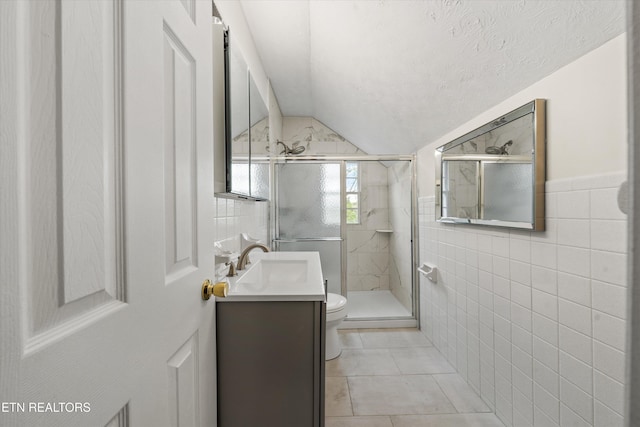 full bathroom featuring toilet, a stall shower, vanity, and tile walls
