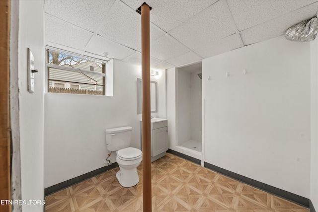 bathroom featuring vanity, baseboards, a paneled ceiling, and toilet