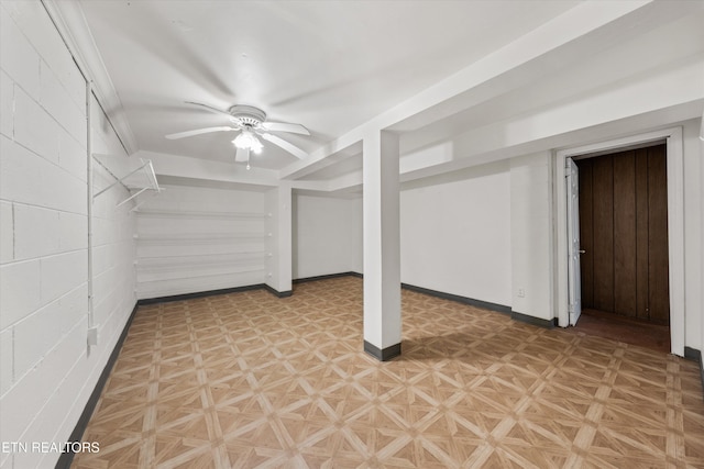 finished below grade area featuring baseboards, a ceiling fan, and light floors