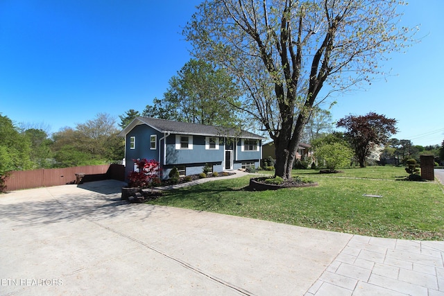 raised ranch with concrete driveway, a front yard, and fence