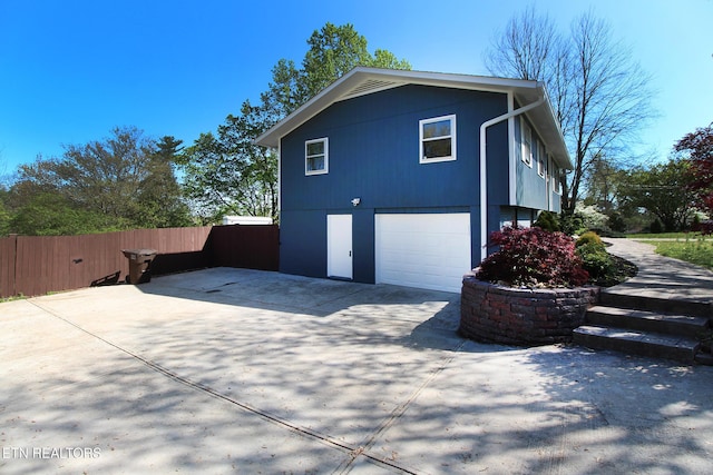 view of side of property with a garage, driveway, and fence