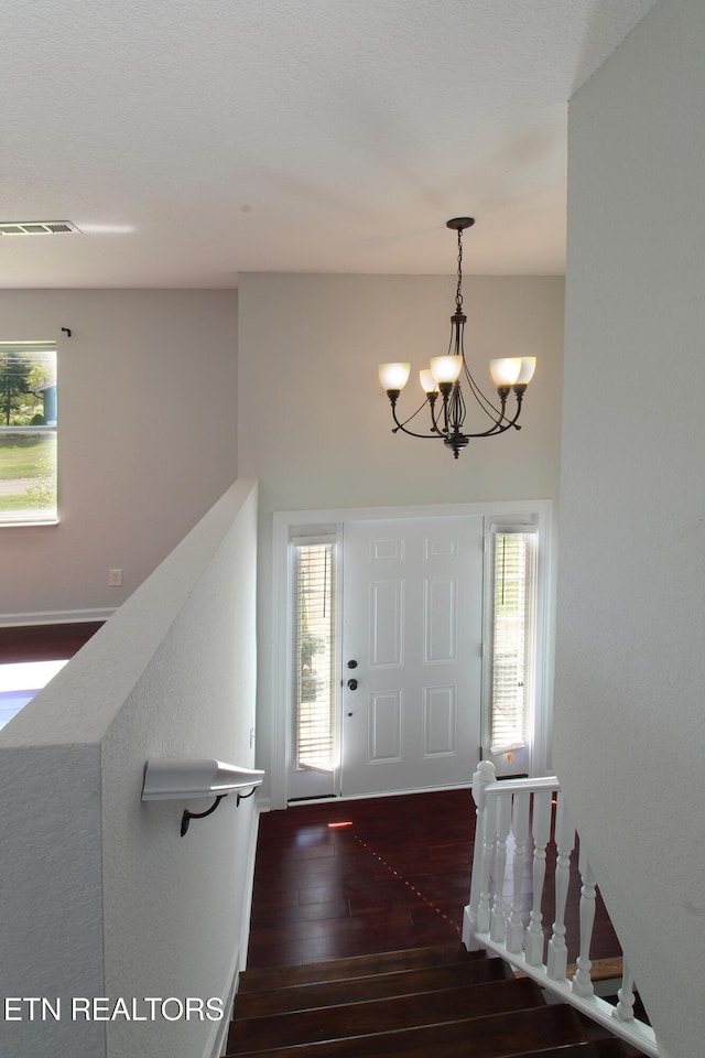 entryway featuring wood-type flooring, plenty of natural light, a notable chandelier, and visible vents