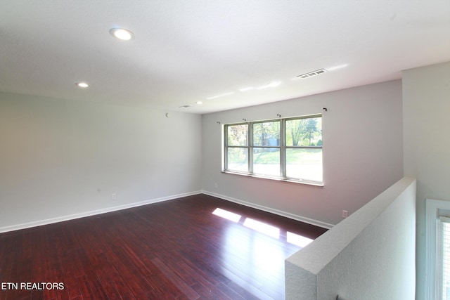 spare room with visible vents, baseboards, recessed lighting, and dark wood finished floors