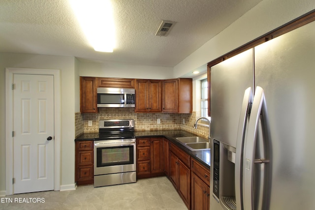 kitchen with a sink, tasteful backsplash, appliances with stainless steel finishes, and dark countertops