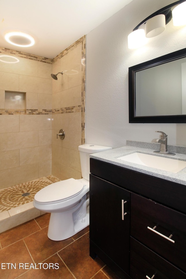 bathroom featuring tiled shower, vanity, and toilet
