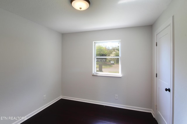 empty room featuring dark wood-style flooring and baseboards