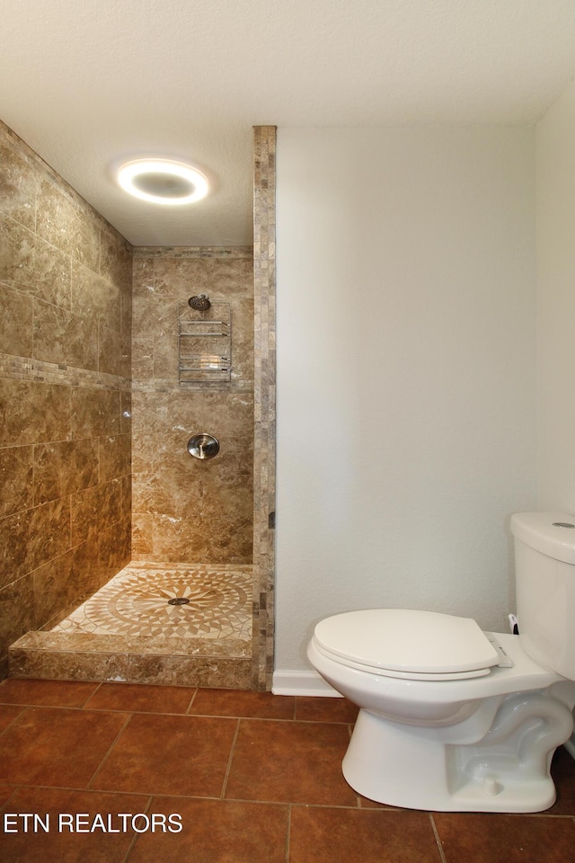 bathroom with toilet, tile patterned floors, and tiled shower