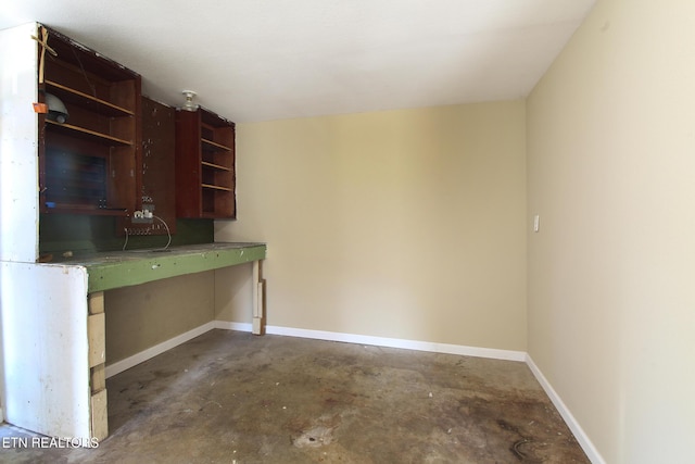 kitchen with baseboards, concrete flooring, and open shelves