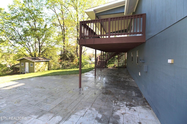 view of patio with a wooden deck, an outdoor structure, and stairway