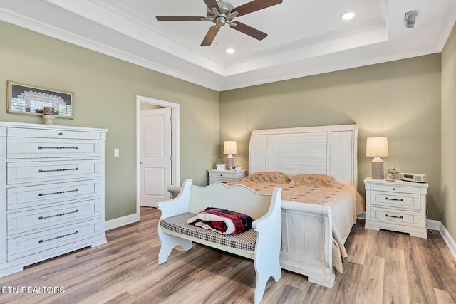 bedroom with a tray ceiling, baseboards, and wood finished floors