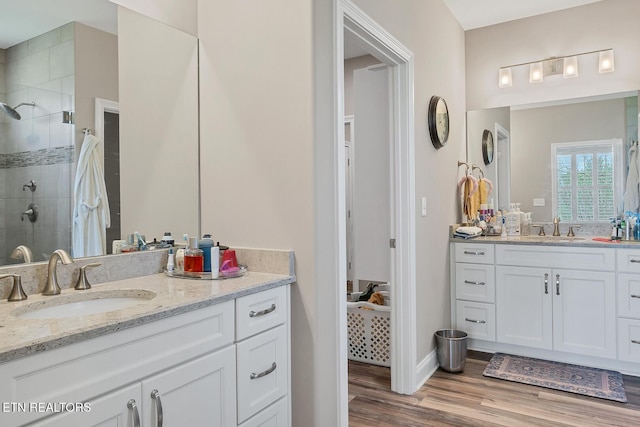 full bathroom featuring a sink, two vanities, a shower stall, and wood finished floors