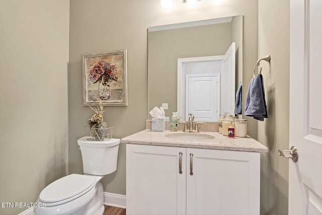 half bathroom with toilet, vanity, and baseboards