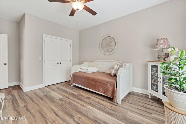 bedroom featuring a closet, baseboards, light wood-type flooring, and a ceiling fan