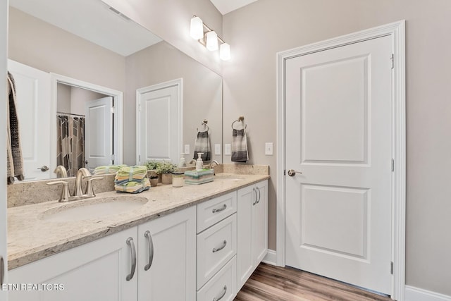 bathroom featuring double vanity, a sink, and wood finished floors