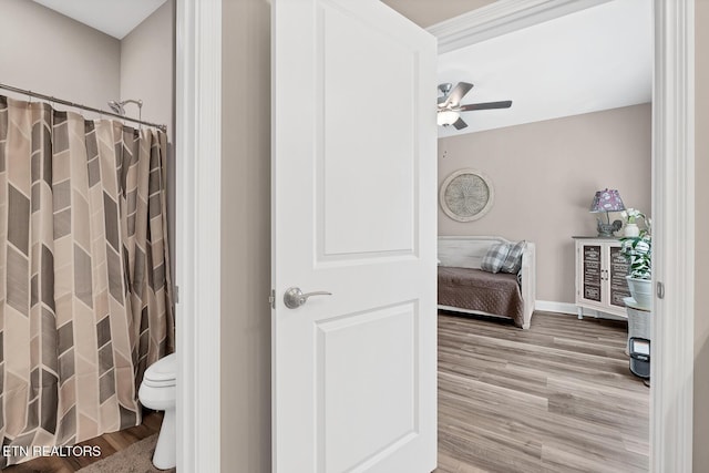 full bath with toilet, wood finished floors, ceiling fan, and a shower with shower curtain