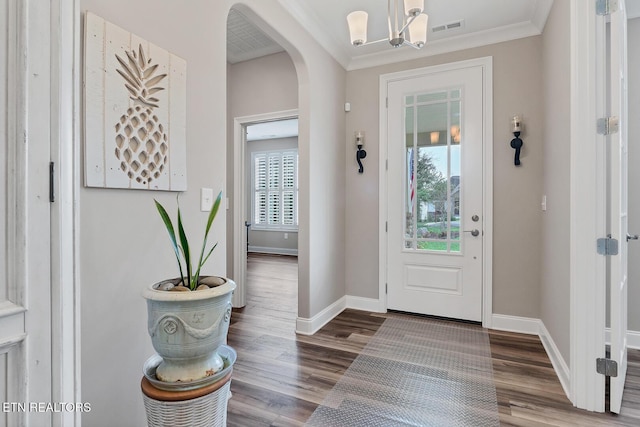 entryway with visible vents, baseboards, arched walkways, crown molding, and wood finished floors