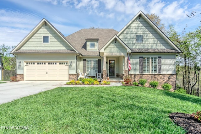craftsman-style home with driveway, stone siding, a front lawn, a garage, and a shingled roof