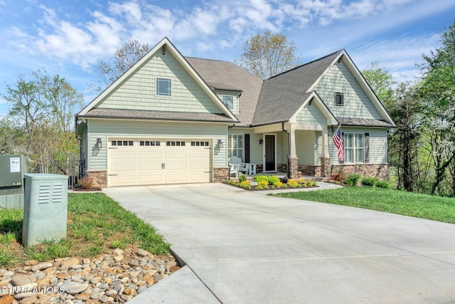 craftsman inspired home featuring a shingled roof, stone siding, covered porch, and concrete driveway