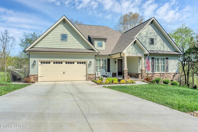 craftsman-style home featuring a front lawn, stone siding, driveway, and roof with shingles