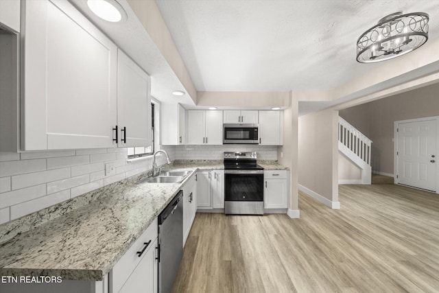 kitchen featuring a sink, stainless steel appliances, white cabinets, baseboards, and backsplash