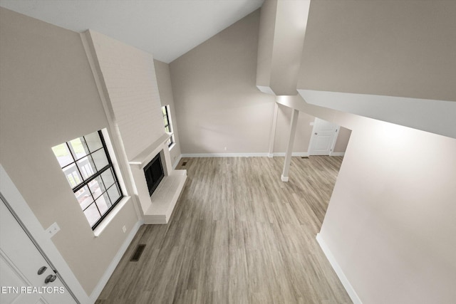unfurnished living room with lofted ceiling, baseboards, visible vents, and wood finished floors