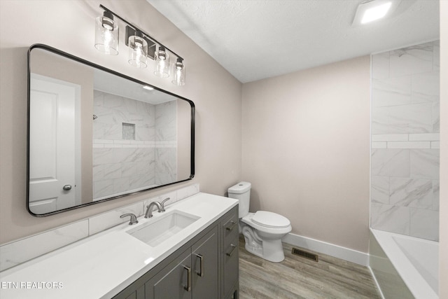 bathroom featuring toilet, wood finished floors, vanity, visible vents, and baseboards