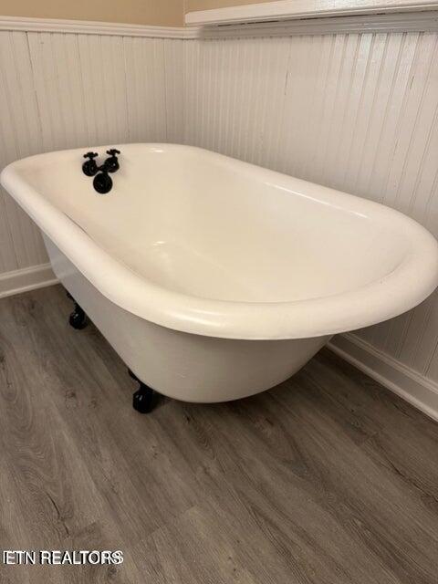 bathroom with a soaking tub and wood finished floors