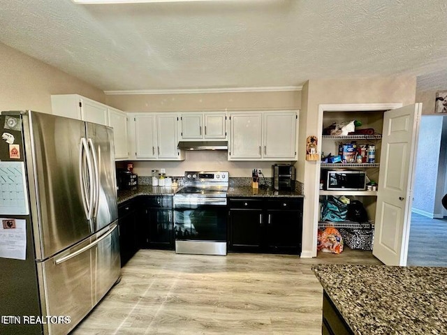 kitchen featuring dark stone countertops, light wood-type flooring, under cabinet range hood, white cabinetry, and stainless steel appliances