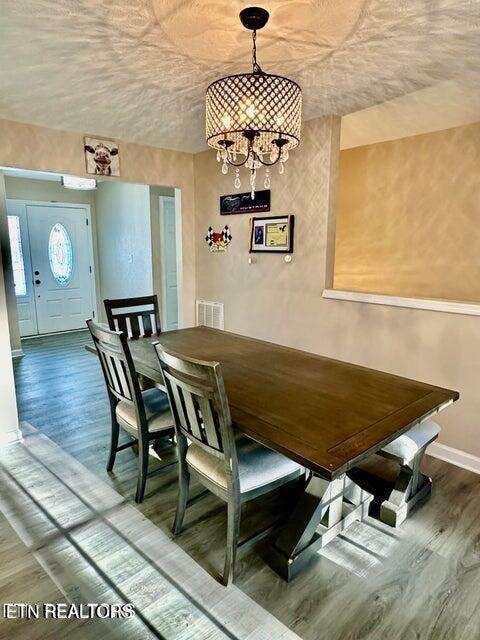 dining area with baseboards, wood finished floors, a notable chandelier, and visible vents
