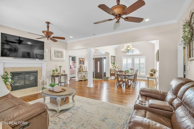 living room featuring ceiling fan with notable chandelier, crown molding, and wood finished floors