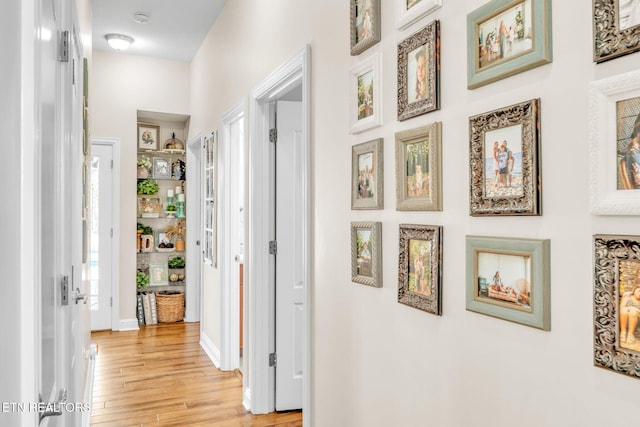 hall with baseboards and light wood-type flooring