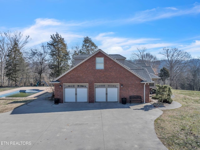 view of property exterior featuring concrete driveway, a jacuzzi, brick siding, solar panels, and a garage