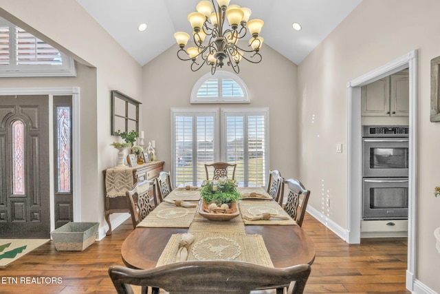 dining space featuring high vaulted ceiling, a notable chandelier, dark wood-style floors, and baseboards