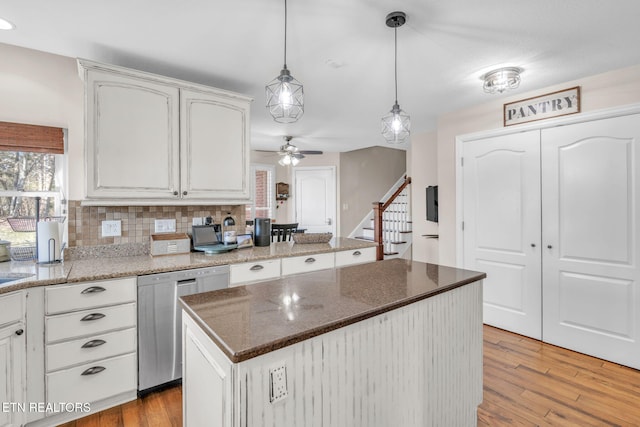 kitchen with decorative light fixtures, light wood-style floors, stainless steel dishwasher, and a ceiling fan